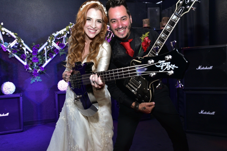 A couple posing with two electric guitars at their Rock 'n Roll wedding reception. 