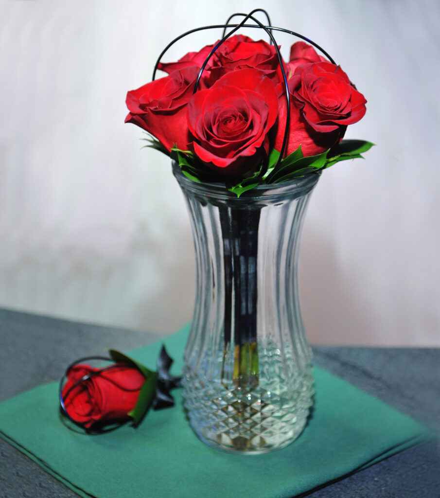 Red roses bundle in clear vase on table at Rock N Roll Wedding Chapel.